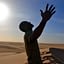 Man experiencing the freedom of the Sahara Desert as the sun looms above his head. Sir Driver Tours. Private tour.